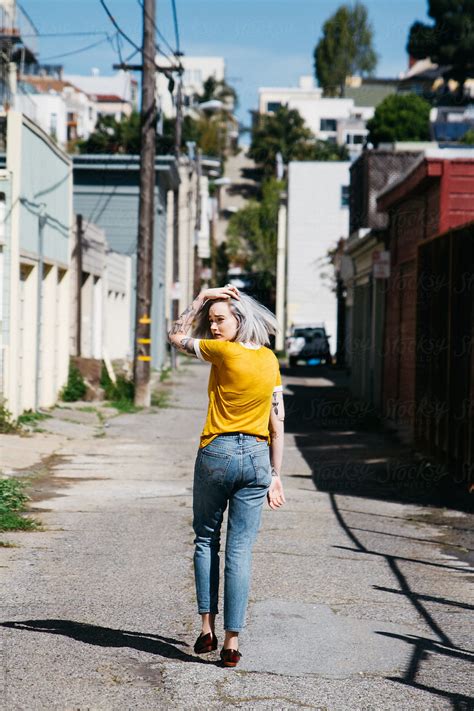 Young Woman Model Walking In Alley Way Bridge With Chain Link Fence By Stocksy Contributor