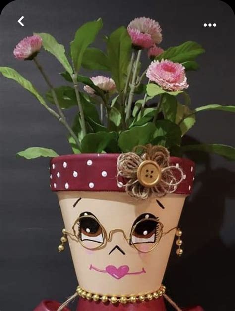 A Potted Planter With Flowers In It And A Face Painted On The Side