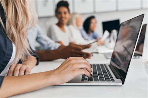 Femme blonde avec une coiffure élégante en tapant du texte sur le clavier au bureau Portrait