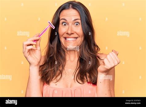Beautiful Brunette Woman Asking For Depilation Holding Shaver Razor Over Yellow Background