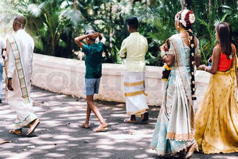 unrecognizable Locals in traditional outfits walk through the Park of ...