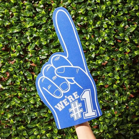 A Person Holding Up A Peace Sign In Front Of A Hedge With The Number 1