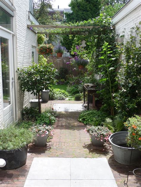 An Outdoor Garden With Potted Plants And Flowers On The Walkway Between