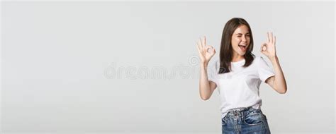 Satisfied Cheerful Brunette Girl Winking Sassy And Showing Okay Gesture In Approval Stock Image