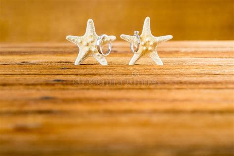 Two Wedding Rings With Two Starfish On Wooden Table Stock Photo Image