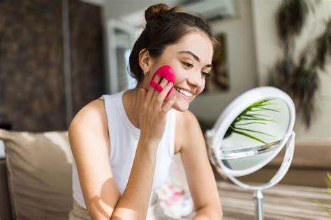 Uma jovem caucasiana sorridente está fazendo uma massagem facial