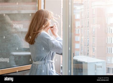 Blonde Woman In Bathrobe Drinking Her Morning Coffee Or Tea On A Downtown Balcony Woman