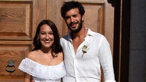 A Man And Woman Standing Next To Each Other In Front Of A Wooden Door