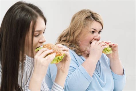 Zwei M Dchen D Nn Und Fett Blond Und Brunette Essen Hamburger Auf Einem Wei En Hintergrund