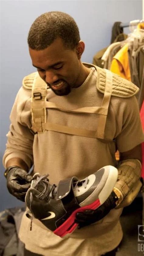 A Man Holding Two Pairs Of Shoes In One Hand And Looking Down At The Other