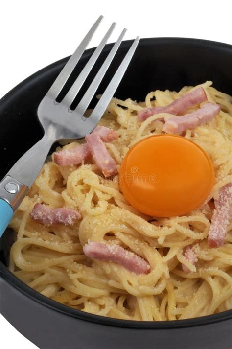 Plate Of Spaghetti Carbonara With An Egg Yolk And A Fork On A White