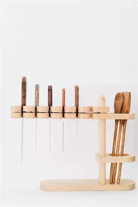 a wooden rack with several pairs of scissors on it and some needles ...