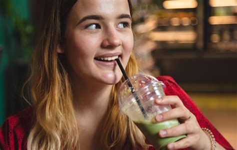 Uma jovem em um café bebe um latte de gelo de bebida verde Foto Grátis