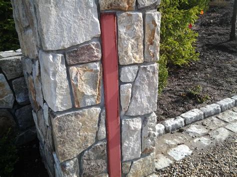 A Stone Wall With A Red Door In The Center And Bushes Behind It On