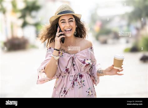 Una joven sonriente y feliz está caminando por la ciudad hablando por