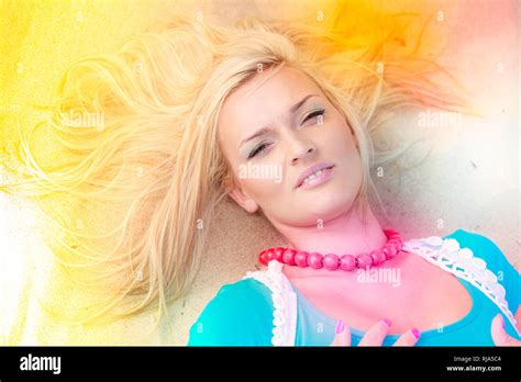 Portrait Of Attractive Blonde Woman Lying On Sandy Beach Relaxing During Summertime Stock Photo