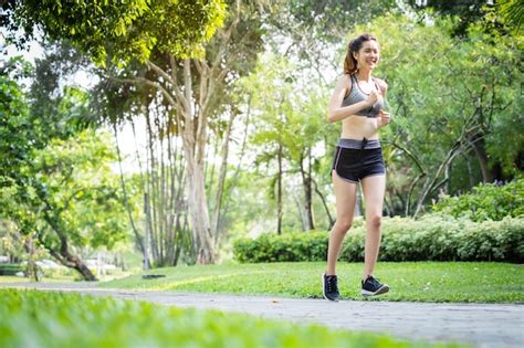 Manhã de jovem esporte asiático mulher correndo ao ar livre no parque