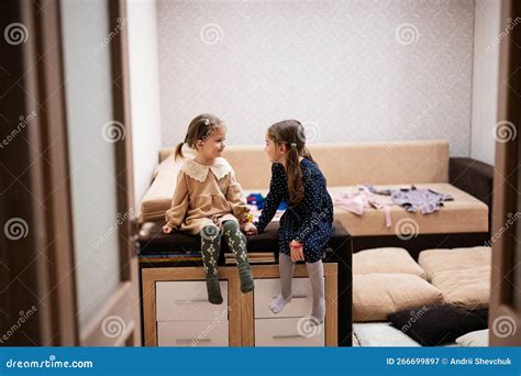 Two Sisters Sit On The Sofa And Tell And Share Girlish Secrets With