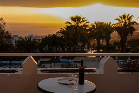 Bottle Of Wine On Table During Sunset With Silhouette Palm Trees In