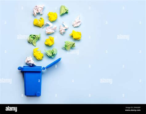 Blue Recycle Bin With Crumpled Colored Paper Balls On A Blue Background