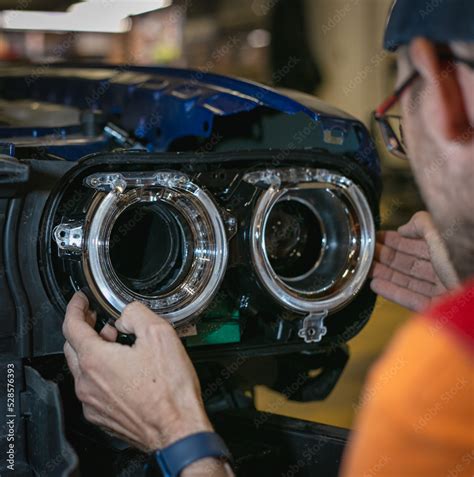 Car headlight in repair close-up. The car mechanic installs the lens in ...