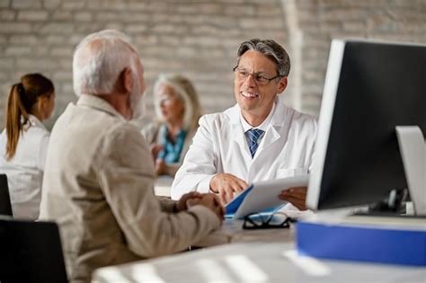 Glücklicher männlicher arzt der seinem älteren patienten während des