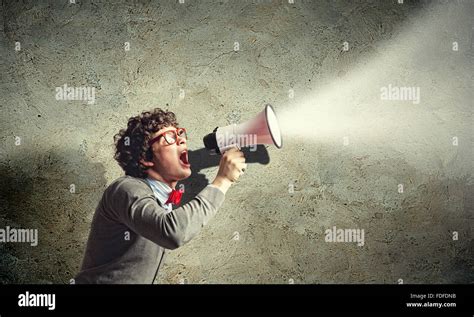 Portrait of young man shouting loudly using megaphone Stock Photo - Alamy