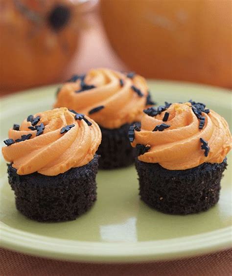 Three Cupcakes With Frosting And Sprinkles On A Green Plate