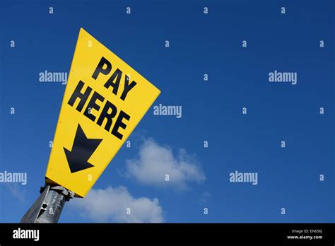 Yellow Pay Here Sign Against A Blue Sky Background With Copy Space