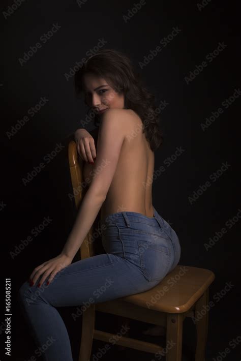 Sexy Topless Lady In Fashionable Jeans Sitting On A Chair Stock Photo