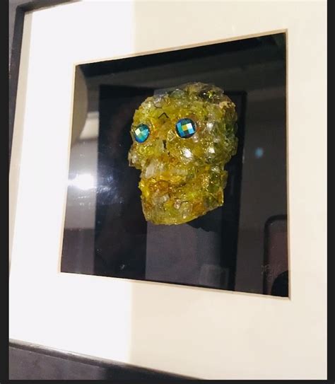 A Glass Skull With Blue Eyes In A Frame