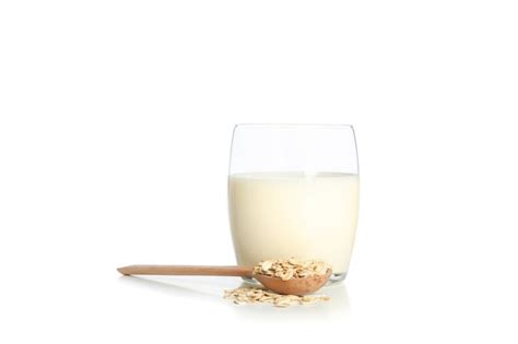 Vaso de leche de avena y una cuchara con avena aislado en blanco | Foto Premium