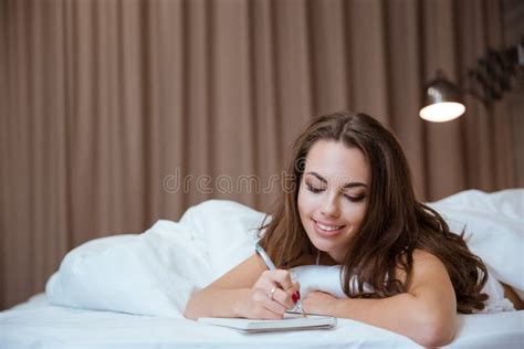 Woman Making Notes In Notepad While Lying On The Bed Stock Image