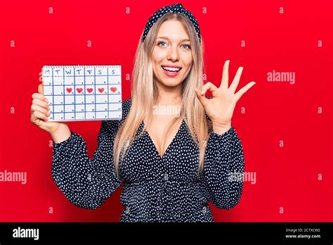 Jeune Femme Blonde Tenant Le Calendrier Coeur Faisant Signe Ok Avec Les Doigts Souriant