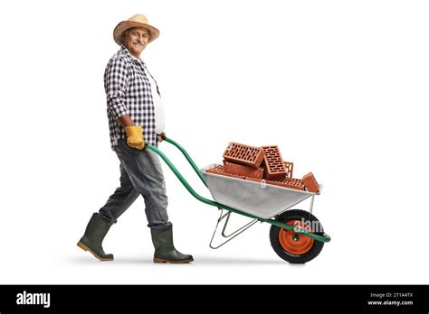 Full Length Profile Shot Of A Mature Gardener Pushing A Wheelbarrow