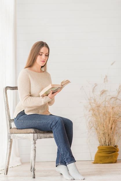 Une Jolie Jeune Femme Assise Sur Une Chaise En Bois Lisant Un Livre