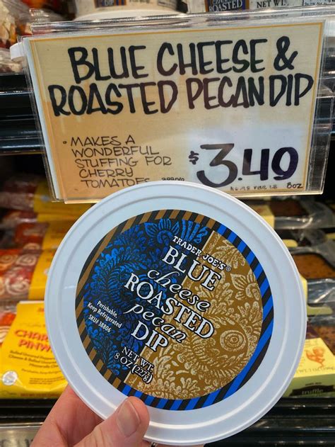 A Person Holding Up A Blue Cheese And Roasted Pecan Dip In Front Of A