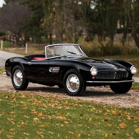 An Old Black Sports Car Is Parked On The Side Of The Road In Front Of