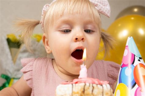 Premium Photo A Twoyearold Girl Blows Out A Candle On A Birthday Cake Makes A Wish