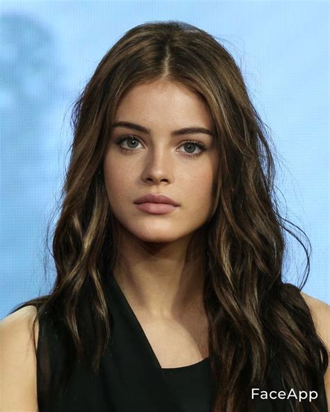 A Woman With Long Brown Hair And Blue Eyes Is Looking At The Camera While Wearing A Black Dress