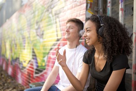 Teenage Couple Listening To Mp Player Against Wall With Graffiti