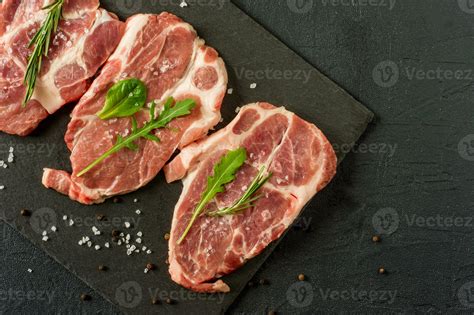 Fresh Raw Pork Chop Meat On A Plack Slate With Rosemary And Parsley And