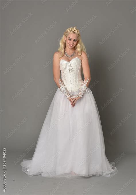 Full Length Portrait Of Blonde Girl Wearing White Corset Gown Standing Pose On Grey Studio