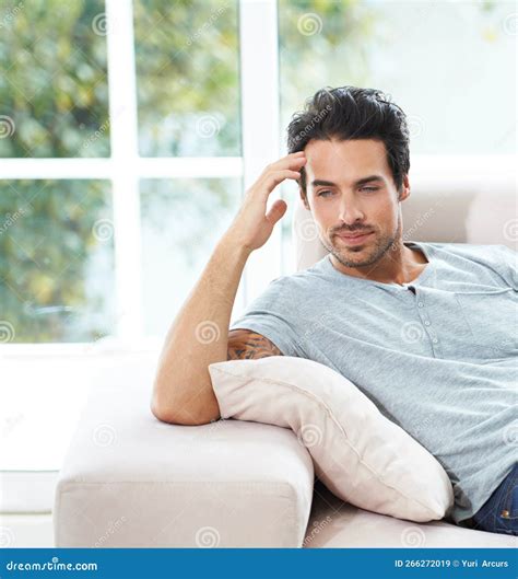 Couch Contemplations A Handsome Young Man Looking Thoughtful While Sitting On The Sofa At Home