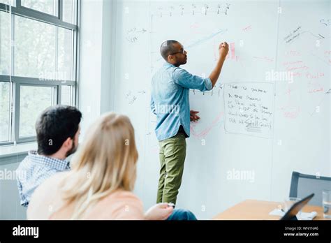 Man Writing On Whiteboard During Board Room Presentation Stock Photo