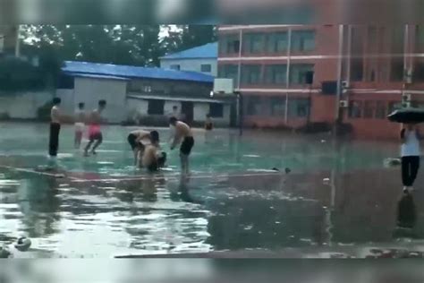 多名高中生暴雨中在学校操场游泳，期间一名学生以冲刺的速度匍匐冲到水中并滑了起来，多名学生围观叫好游泳操场速度