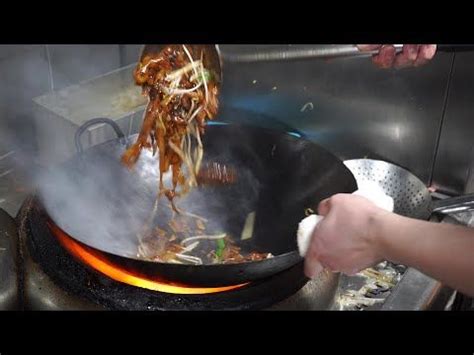 Someone Is Cooking Food In A Wok On The Stove