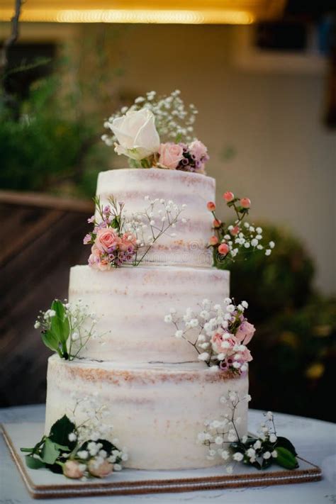 White Three Tiered Naked Wedding Cake With Tiny Pink Orange Roses Decoration Stock Photo