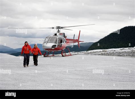 Helicopter tour guides walk from helicopter on top of Mendenhall Glacier near Juneau, Alaska ...