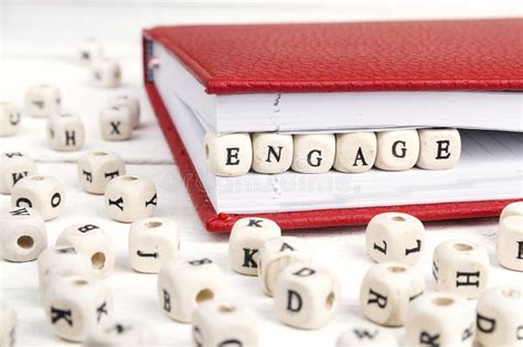 Word Engage Written In Wooden Blocks In Notebook On White Wooden Stock